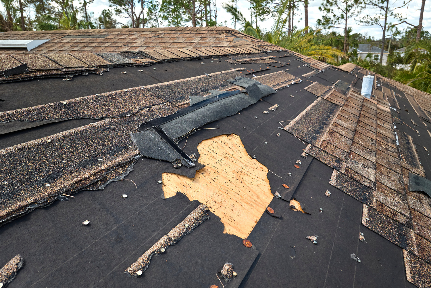 Damaged house roof with missing shingles after hurricane Ian in Florida. Consequences of natural disaster